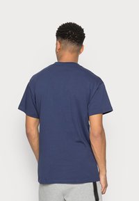 Tmavě modré bavlněné tričko s kulatým výstřihem a krátkými rukávy, s hladkou texturou a volným střihem, pohled zezadu.