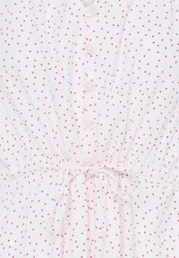 Robe en tissu blanc à petits pois rouges, avec boutons sur le devant, taille à cordon de serrage et deux poches latérales.