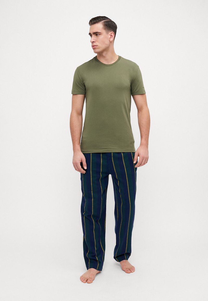 Olive green cotton t-shirt paired with navy striped pajama pants featuring yellow lines. Loose fit and casual design with short sleeves.