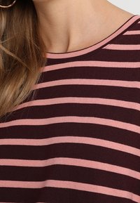 Bordeaux- und rosa gestreifter Strickoberteil mit Rundhalsausschnitt. Der Stoff ist weich und hat eine glatte Textur, mit gleichmäßigen, horizontalen Streifen.