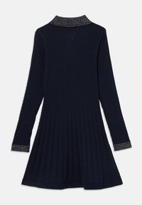 Rochie tricotată navală cu mâneci lungi, un finisaj texturat și un guler și manșete sclipitoare. Siluetă în formă de A. Vedere din spate prezentată.