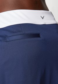 Námořnické šortky s bílým pasem a malým logem. Texturovaná látka s detailní zadní kapsou a hladkým povrchem.