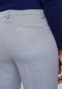 Lehké kalhoty s texturovaným bílým a námořnickým vzorem, s jednou zadní kapsou a rovnými nohavicemi.