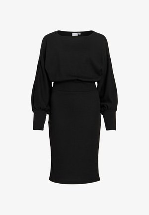 Svart klänning med långa ärmar, lös överdel och figursydd kjoldel. Tillverkad av stickat tyg, med rund halsringning och rynkade ärmar.