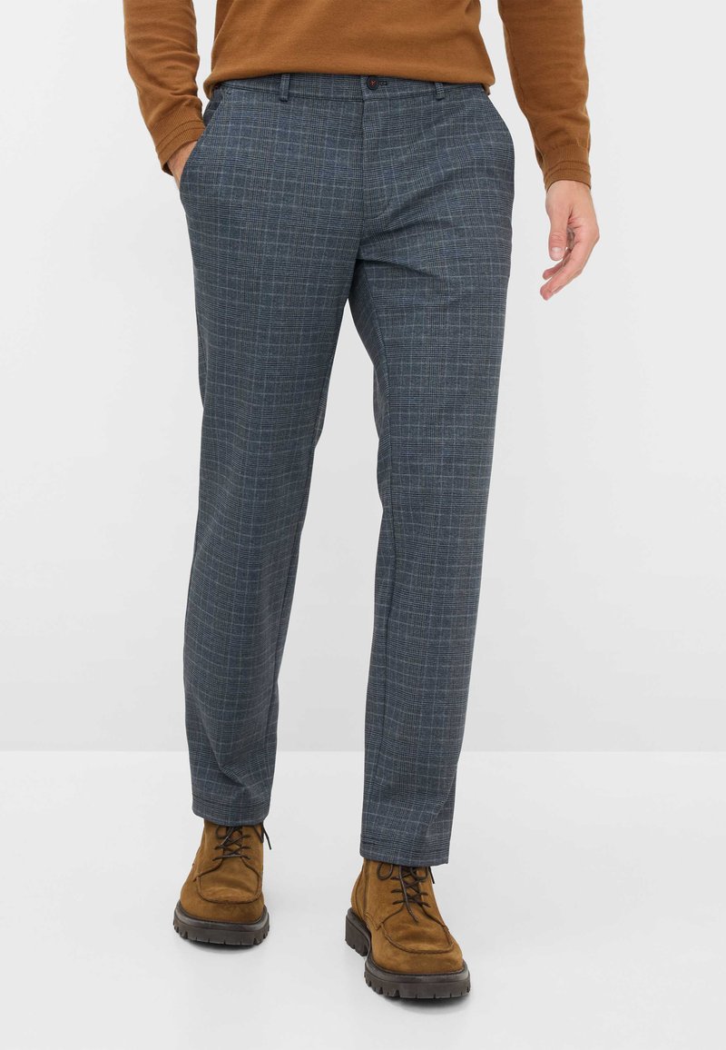 Pantaloni a quadri grigi con vestibilità sartoriale, parte anteriore liscia, tasche laterali e una trama sottile, abbinati a stivali in suede marrone.