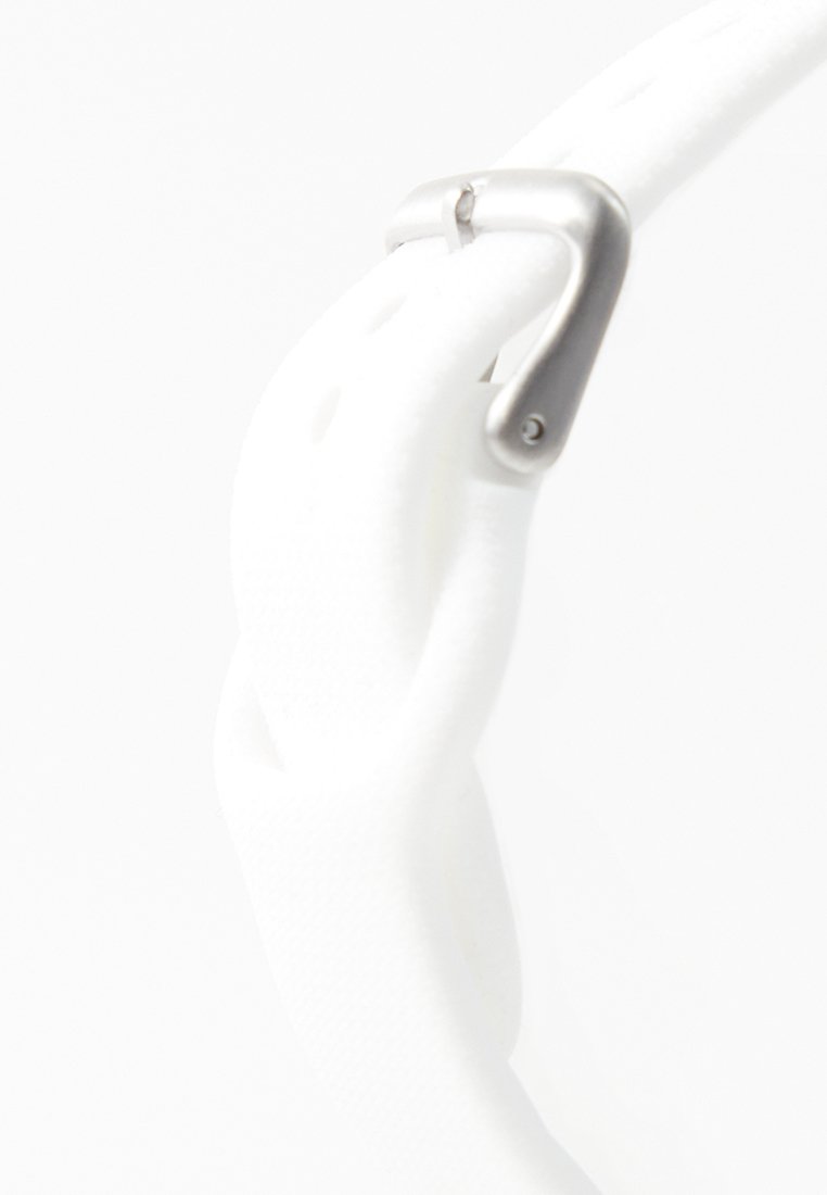 Cinturón de tela blanca pasado por una hebilla de metal plateado sobre un fondo blanco liso.