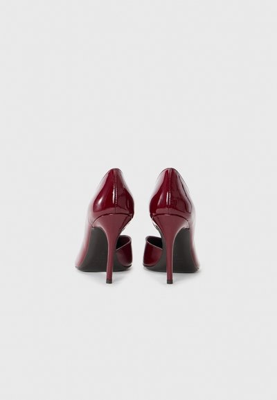 Glossy burgundy patent leather high heels with pointed toes and slim stiletto heels, showcasing smooth texture and sleek design.