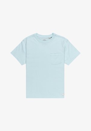 Jasnoniebieska koszulka z krótkim rękawem z kieszonką na piersi, zestawiona z luźnymi czarnymi spodniami i białymi trampkami. Prosty design, materiał bawełniany.