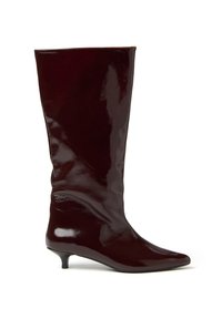 Bota de cuero marrón oscuro brillante hasta la rodilla, con puntera afilada y tacón bajo, mostrada de lado sobre un fondo blanco.