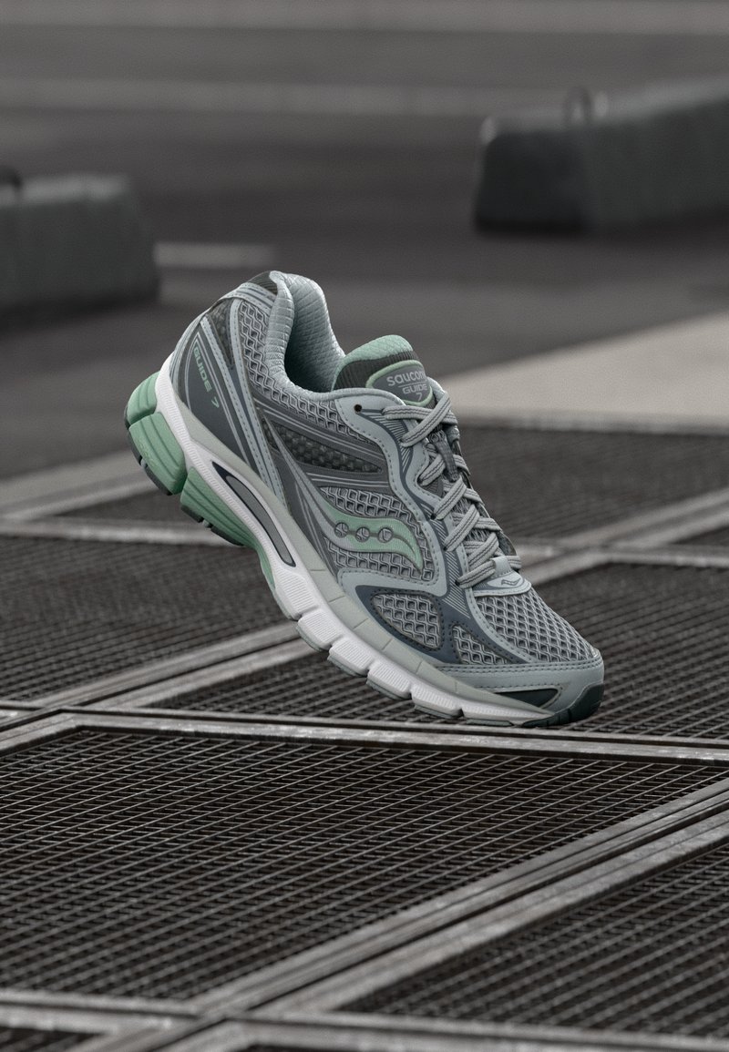Γκρι αθλητικό παπούτσι για τρέξιμο με επάνω μέρος από δίχτυ, λεπτομέρειες σε μέντα και μαλακή σόλα. Διαθέτει ενισχυμένες περιοχές στη μύτη και τη φτέρνα για υποστήριξη.