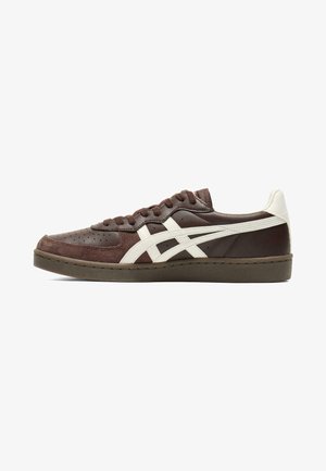 Low-profile brown sneaker with white side stripes, suede detailing, and brown laces on a dark rubber sole against a white background.