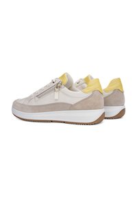 Beige und hellgraue Sneakers aus Wildleder und Leder mit einem gelben Fersenakzent und einem seitlichen Reißverschluss, auf einer weißen und braunen Sohle.
