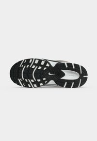 Η σόλα ενός ασπρόμαυρου παπουτσιού Nike για τρέξιμο με υφασμένο πέλμα και ορατό λογότυπο Nike στο κέντρο.