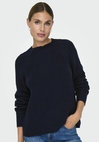 Marineblauer gestrickter Pullover mit gerippter Textur, rundem Ausschnitt und langen Ärmeln. Leicht oversized Passform mit entspannter Silhouette.