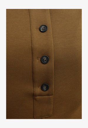 Camicia di cotone marrone con una patta dotata di quattro bottoni neri e una piccola tasca, caratterizzata da una trama liscia e un design aderente.