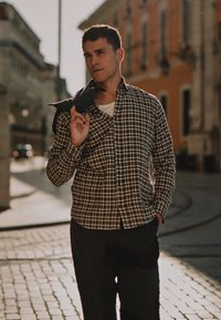 Juodai balto languoto marškinėlių su apykakle, derinami su tamsiomis kelnėmis. Marškiniai dėvimi atidaryti, virš balto marškinio.