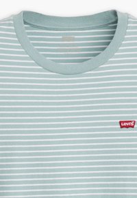 Šviesiai mėlyna dryžuota marškinėlių su apvaliu iškirpimu, turinti plonus baltus dryžius ir raudoną Levi's logotipą kairėje krūtinės pusėje. Minkšta medvilnės medžiaga.