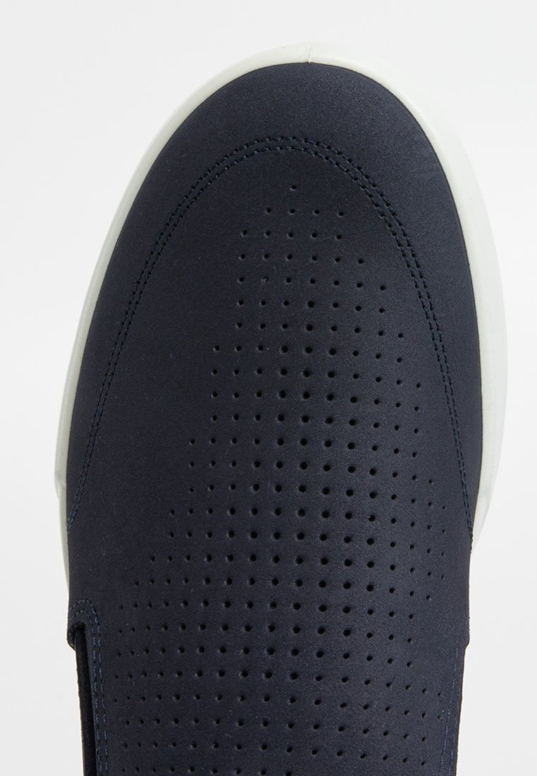 Granatowe buty wsuwane z gładkiej syntetycznej cholewki z małymi perforacjami oraz białą gumową podeszwą. Okrągły nosek i minimalistyczny design.