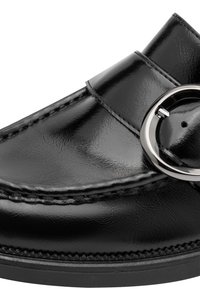 Mocassin en cuir noir brillant avec une large lanière et une grande boucle argentée sur une semelle épaisse.