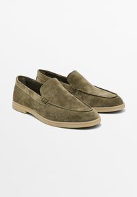 Baskets à enfiler en daim vert olive avec une texture lisse, un bout arrondi et des coutures minimales. Équipées d'une semelle en caoutchouc beige clair pour le confort.