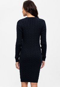 Kabelgebreide jurk in donkermarineblauw, met lange mouwen, een ronde halslijn en een aansluitende pasvorm met textuuroverlays op de stof.