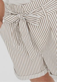 Béžové a bílé vertikálně pruhované šortky s uvázaným látkovým opaskem a kapsami, nošeny s světlým topem.