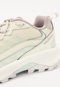 Helle Netzsneaker mit dezenten grünen Akzenten, strukturiertem Sohlenbereich und reflektierenden Details. Verfügt über integrierte Schnürung und Branding.
