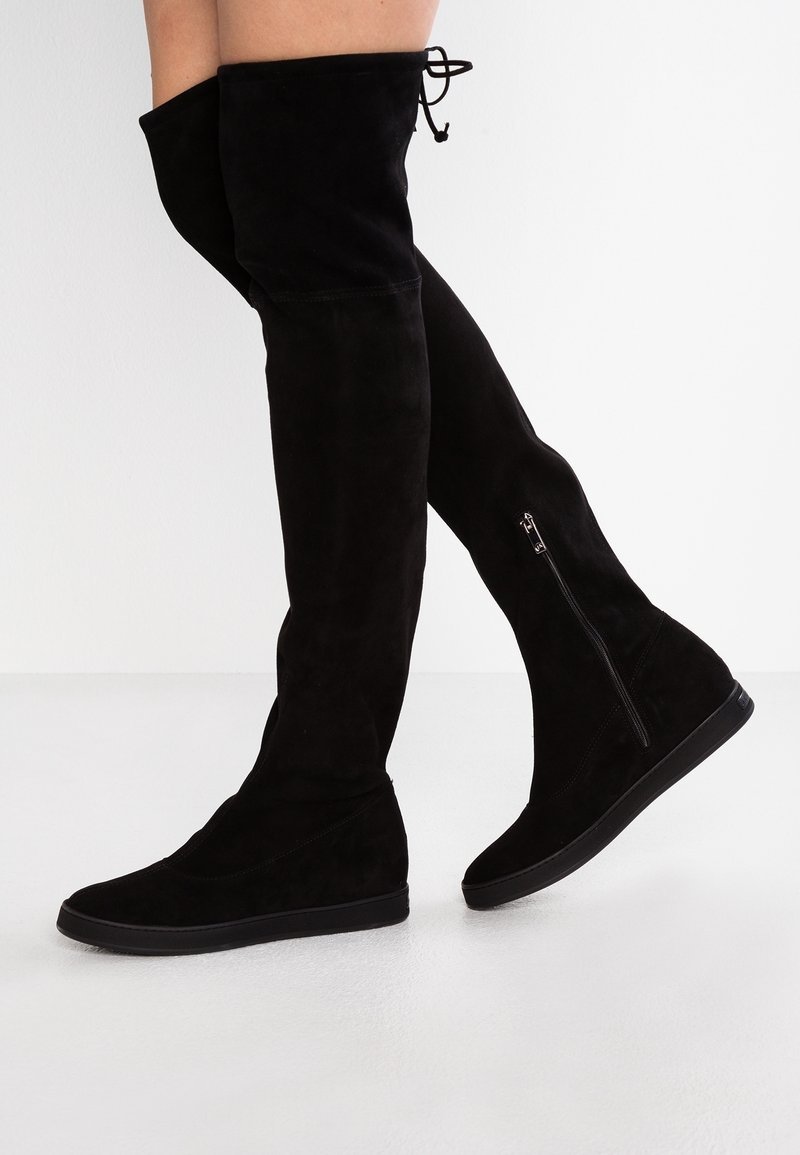 Bottes noires cuissardes en daim, dotées d'un design élégant, d'une forme structurée, d'une fermeture éclair intérieure et d'une semelle plate pour le confort.