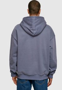 Svetlo šedá oversized mikina s veľkou kapucňou, ribbed manžetami a klokankovým vreckom, vyrobená z jemnej zmesi bavlny.