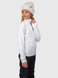 Bambino che indossa un pullover bianco in fleece e un berretto di maglia beige, in piedi contro uno sfondo chiaro e uniforme, che guarda di lato.