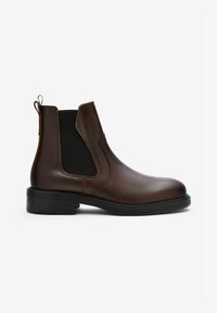 Bruine leren Chelsea-boot met zwarte elastische zijpanelen, trekloops aan de hiel en enkel, en een zwarte rubberen zool.