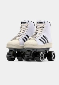 Λευκά ρόλερ σκι με μαύρες λεπτομέρειες, ψηλή σχεδίαση, καμβά στην επάνω πλευρά, καουτσούκ προστατευτικό για τα δάχτυλα και μαύρους τροχούς με λευκή επωνυμία.