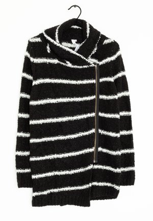 Pull rayé noir et blanc en tissu doux et texturé, doté d'un large col replié et d'une fermeture éclair sur le côté.