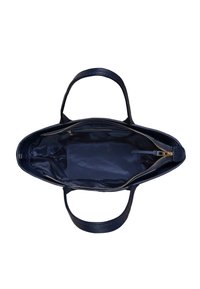 Granatowa skórzana torba tote z podwójnymi uchwytami, otwarta, aby odsłonić gładką podszewkę i zamykaną na zamek kieszeń po jednej stronie.