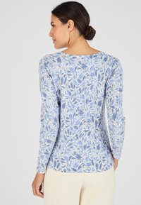 Camicia a maniche lunghe di colore azzurro chiaro con un motivo floreale in bianco e blu scuro. Tessuto morbido con scollo tondo e vestibilità slim.