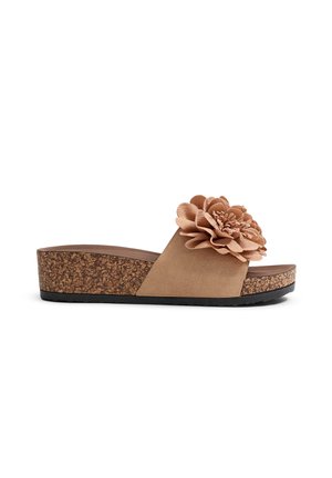 Sandal de plataforma de corcho con una correa de ante beige y un gran acabo de flor de tela. Presenta una suela marrón texturizada y diseño de punta descubierta.