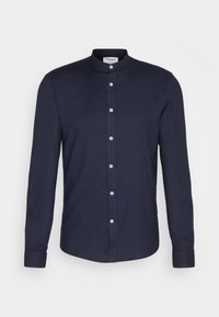 Camicia a maniche lunghe blu navy con colletto a fascia, dotata di chiusura con bottoni e bottoni chiari. Tessuto morbido.