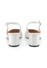 Sandali con tacco bianco dal finish liscio, con cinturino alla caviglia e tacco a blocco. La suola presenta un accento nero. Design minimalista e contemporaneo.