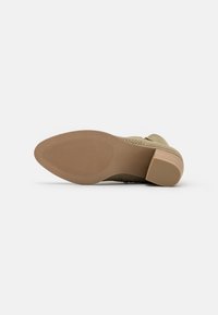 Grøn sammenvævet sko med en lav, struktureret hæl og en gummisål. Har en glat finish og diskret detaljer på overdelen.