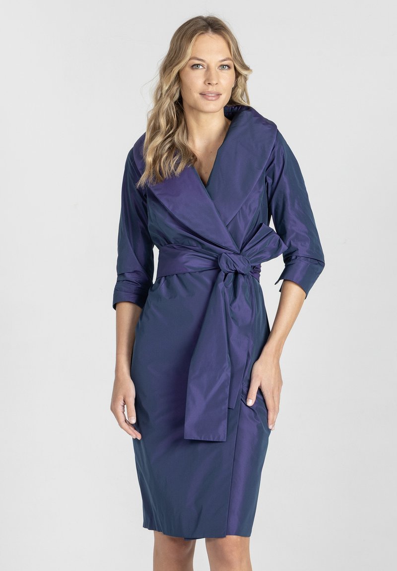 Głęboko fioletowa sukienka kopertowa uszyta z gładkiego, błyszczącego materiału, z rękawami o długości 3/4 oraz związanym paskiem w talii, z dekoltem w kształcie litery V.