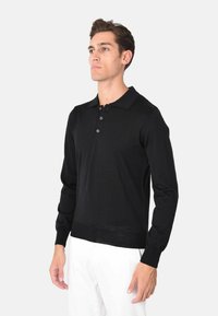 Maglietta polo nera a maniche lunghe con collo alla francese, patta con tre bottoni e polsini a coste. Texture liscia, design aderente.