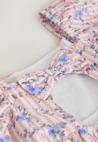 Rožnato-bela tkanina s črtami in majhnim modro-rožnatim cvetličnim vzorcem, z zavezanim pentljam in naborkom z elastičnim zaključkom.