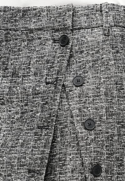 Black and white textured skirt featuring a woven pattern, with a straight cut, a smooth waistband, and three black buttons on the front.