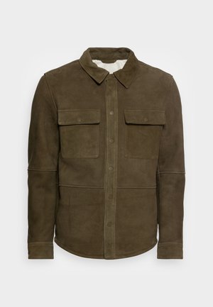 Brązowa zamszowa kurtka z kołnierzem, zapięciami na guziki i dwoma dużymi przednimi kieszeniami z klapkami, prezentowana na jasnym, jednolitym tle.