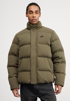 Olive green puffer jacket with a high collar, featuring a zip closure, quilted design, and a small black Nike logo on the chest.