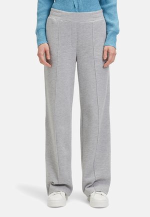 Hellgraue Sweatpants mit weitem Bein, ausgestattet mit vertikalen Nähten und einer glatten Textur. Kombiniert mit weißen Sneakers.
