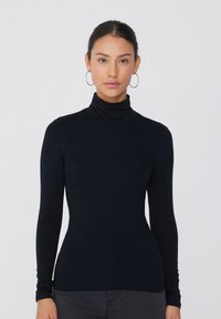 Haut à col roulé noir en tissu lisse et extensible. Manches longues avec une silhouette ajustée et un design de col replié. Simple et polyvalent.