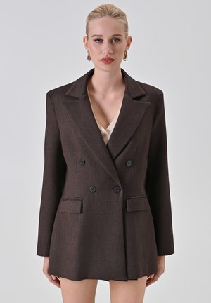 Bruin dubbelbijeen blazer met grote revers, twee voortassen en een gestructureerde stof. Voorzien van zwarte knopen en een kortere snit.