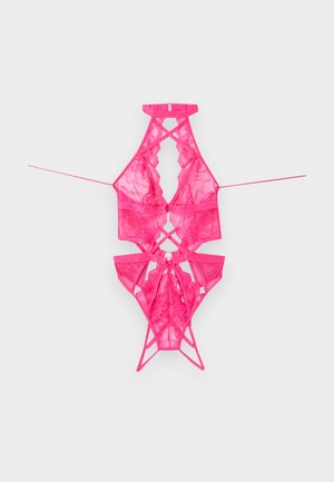 Horúce ružové čipkované teddy s golierom halter, prekríženými ramienkami a sieťkovanými panelmi, položené na šedom pozadí.