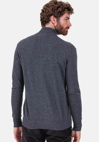 Grauer Strickpullover mit hohem Kragen, gerippten Bündchen und Saum. Weiche Textur, figurbetontes Design und lange Ärmel. Ansicht von hinten.